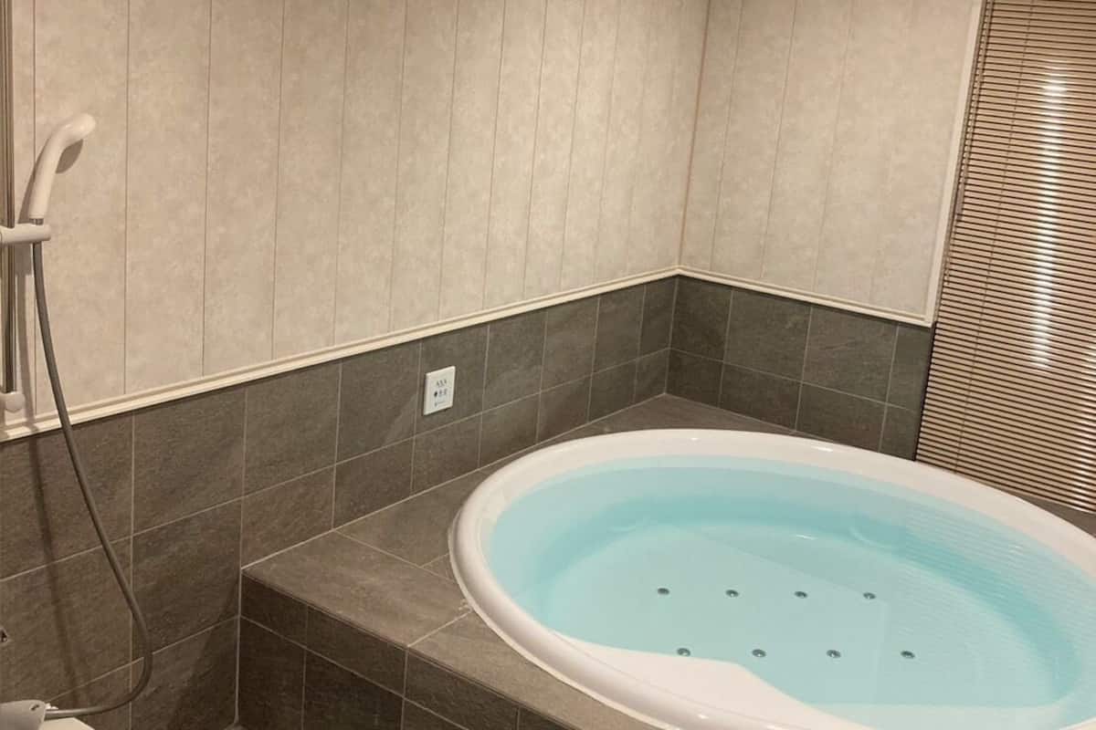 A modern bathroom with a freestanding bathtub, a showerhead, and a toilet.