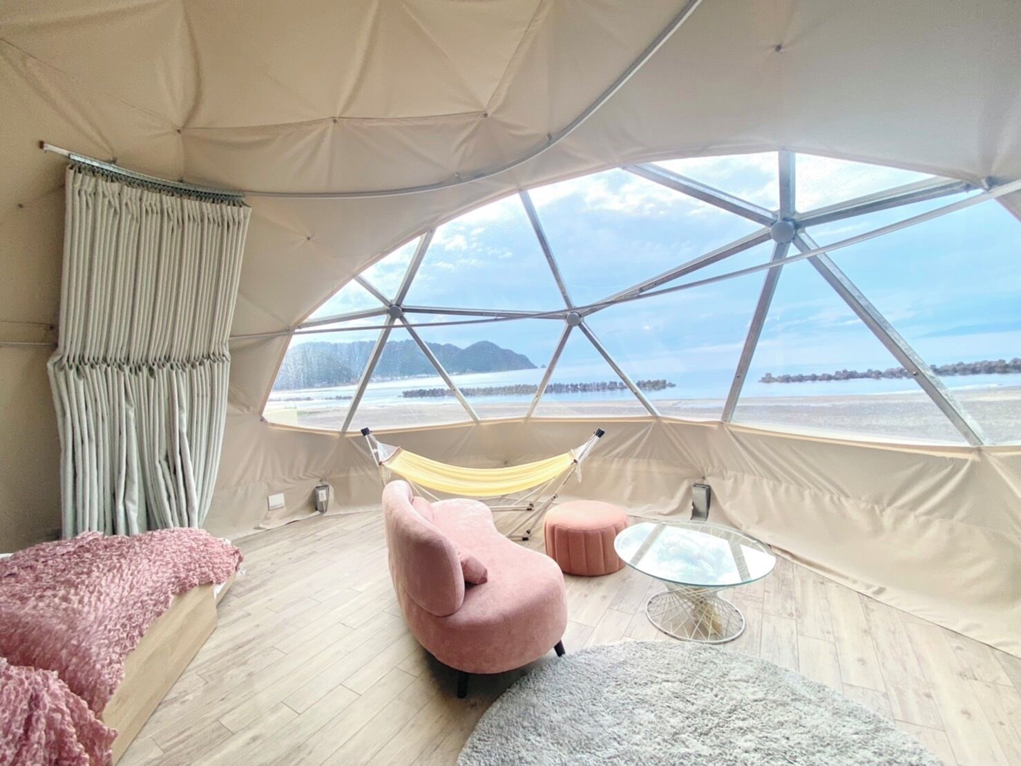 A tent with a panoramic view of a beach and mountains.