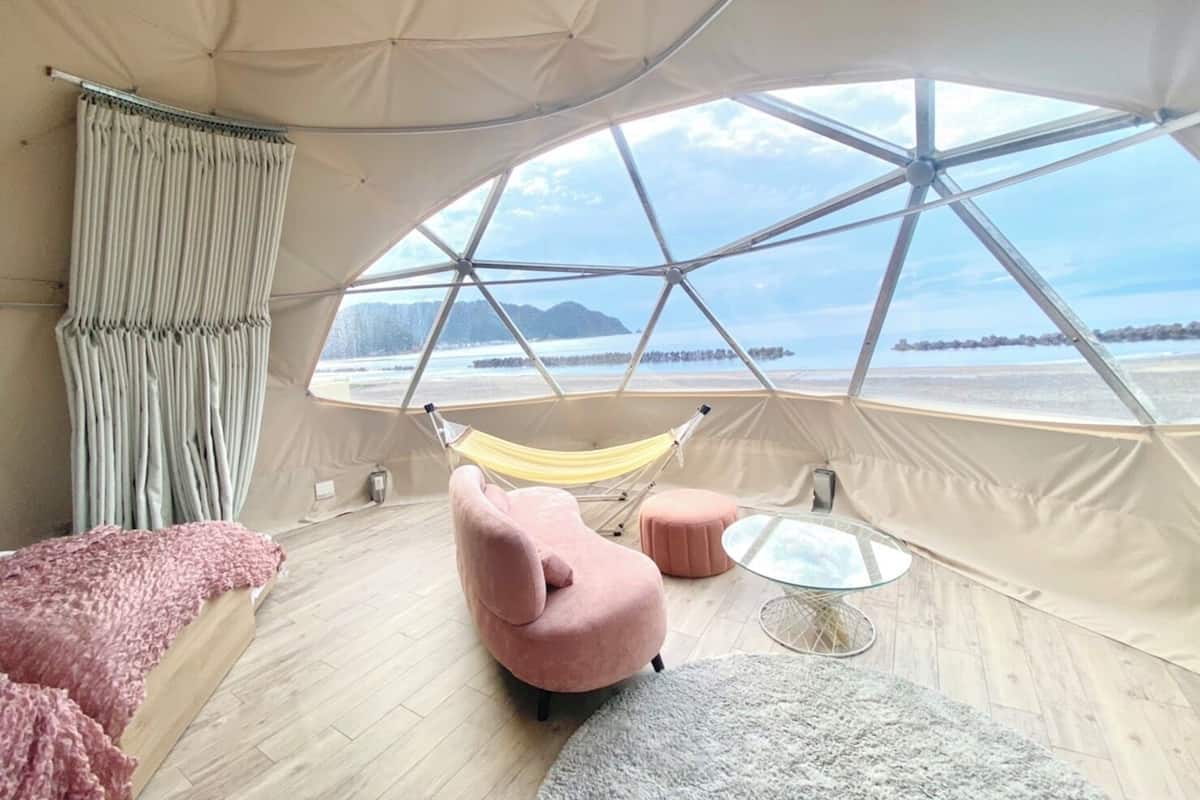 A tent with a panoramic view of a beach and mountains.