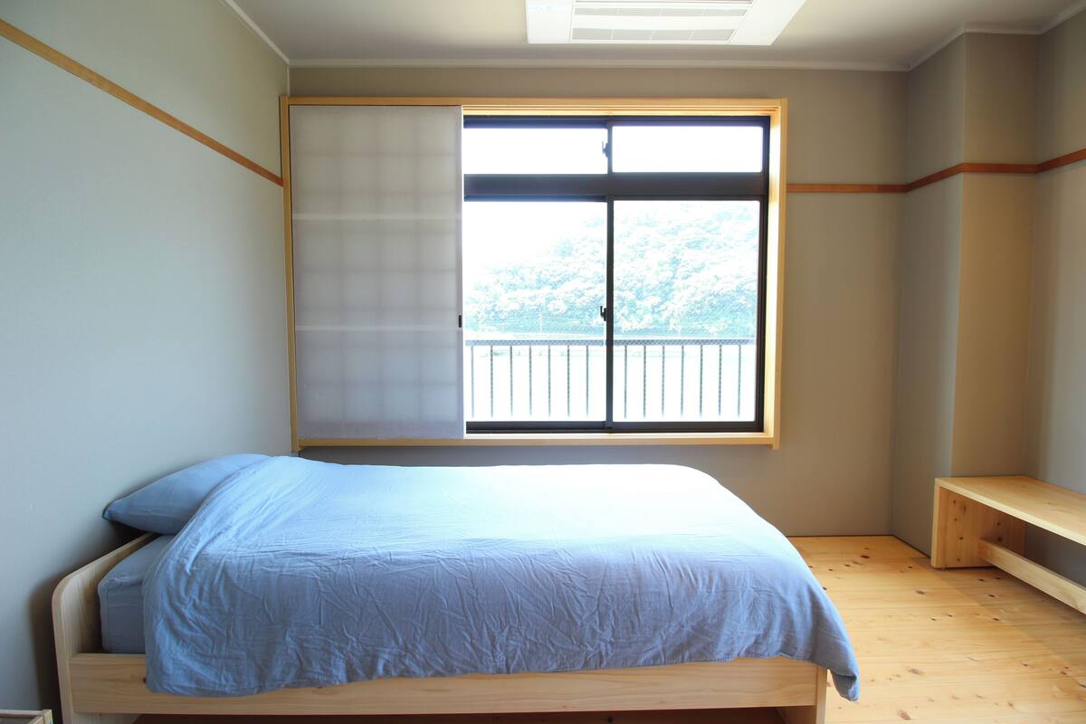 A bedroom with a bed, a window, and a wooden bench.