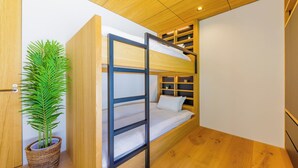 A bunk bed with a wooden headboard, a potted plant, and built-in shelving. - Credence Chalets (Hakuba)