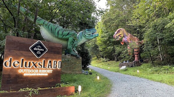A wooden sign for 'deluxsLABO OUTDOOR RESORT' with a dinosaur sculpture. - Deluxs Outdoor Resort Kyotango Kumihama Labo (Kyotango)