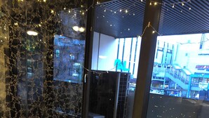 Een kamer met twee witte lederen stoelen, een glazen tafel en een stadsgezicht door grote ramen.