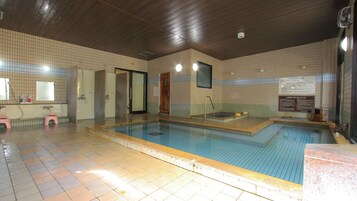 Una piscina interior con paredes y suelo de baldosas, y techo de madera.