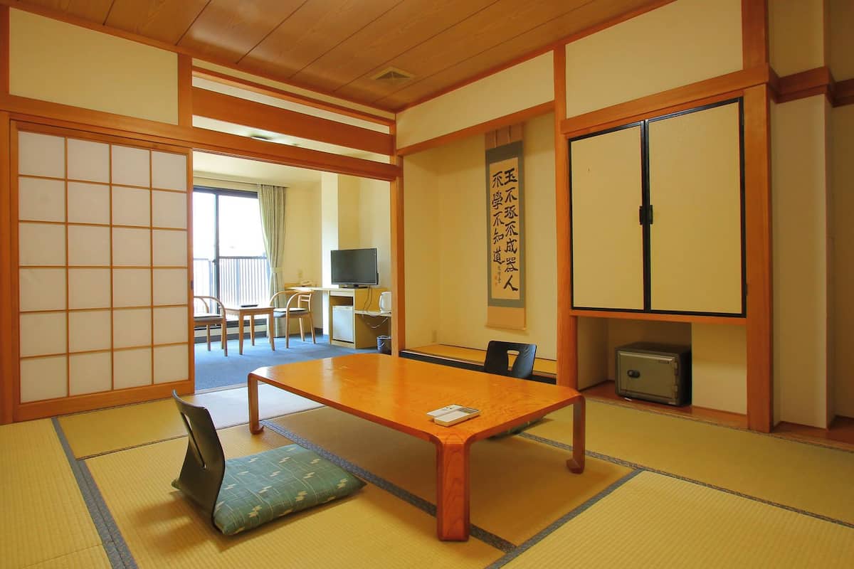 Une pièce de style japonais traditionnel, avec un sol recouvert de tatamis, une table basse, un téléviseur et des portes coulissantes.