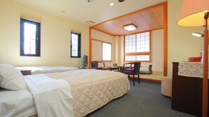 Ein Hotelzimmer mit zwei Betten, einem Schreibtisch, einem Stuhl, einem Fernseher und einem Fenster.