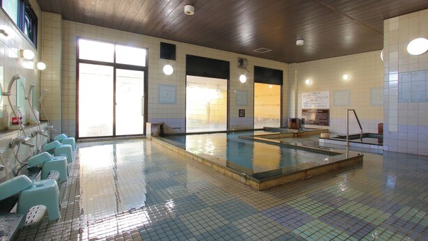 Ein öffentliches Schwimmbad mit mehreren Umkleideräumen, einem großen Hallenbad und gefliesten Wänden.