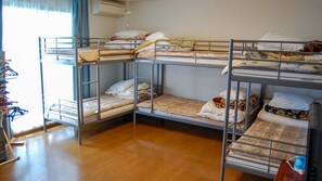 A dormitory room with bunk beds, a wooden floor, and a window with curtains. - Nasu Sports Garden (Nasu)