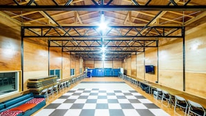 A spacious hall with a checkered floor, rows of chairs, and a long table.