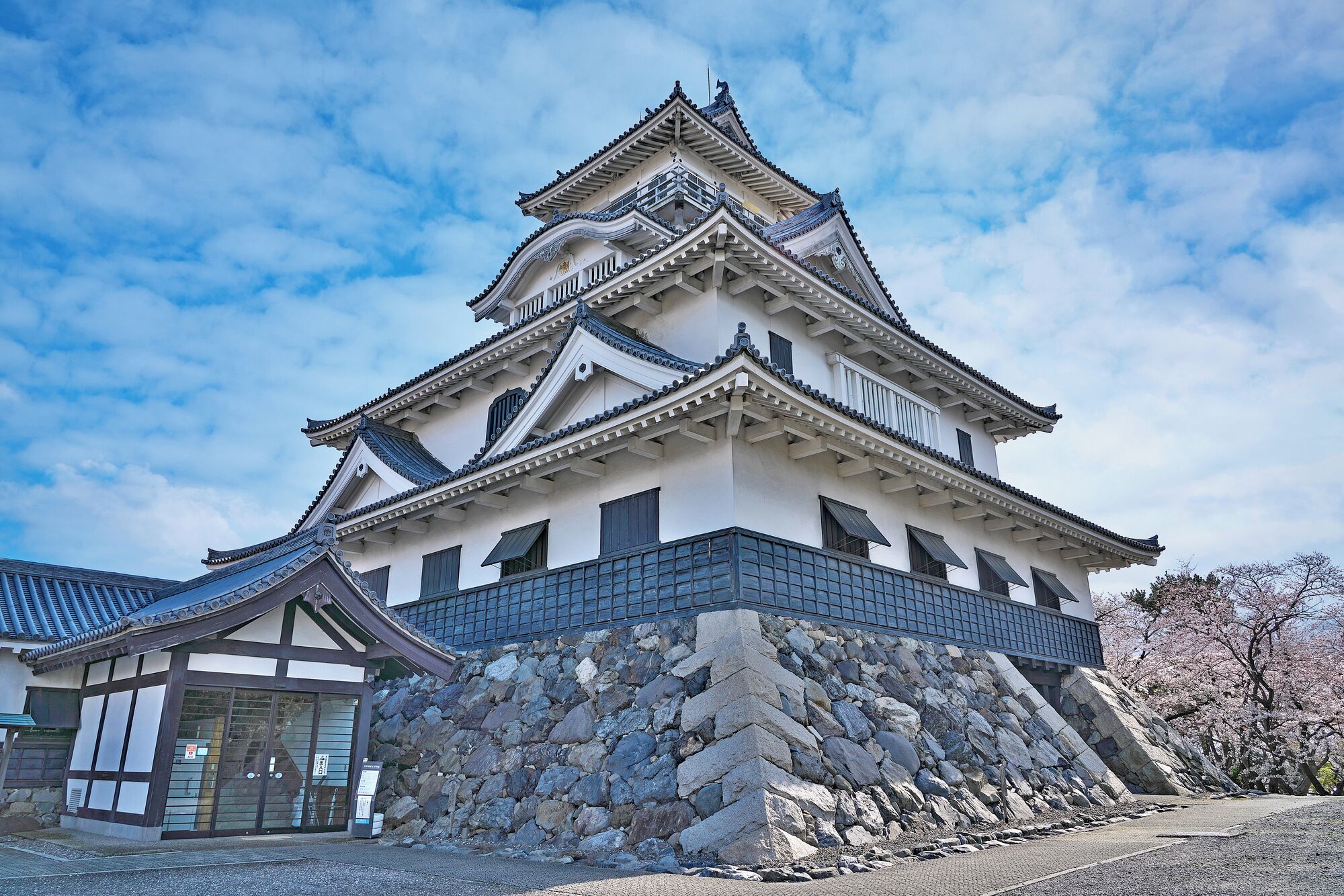 A traditional Japanese castle with multiple levels, stone walls, and a prominent central tower.