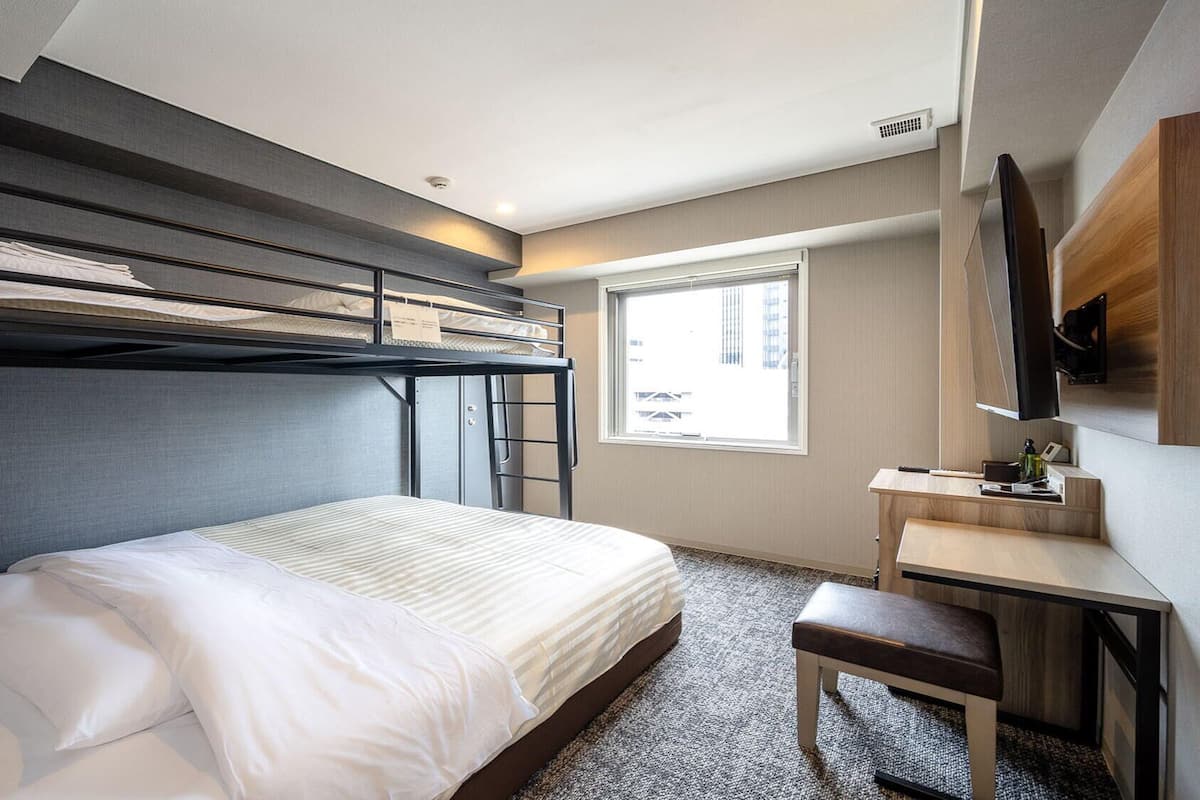 A bunk bed room with a desk and a TV.