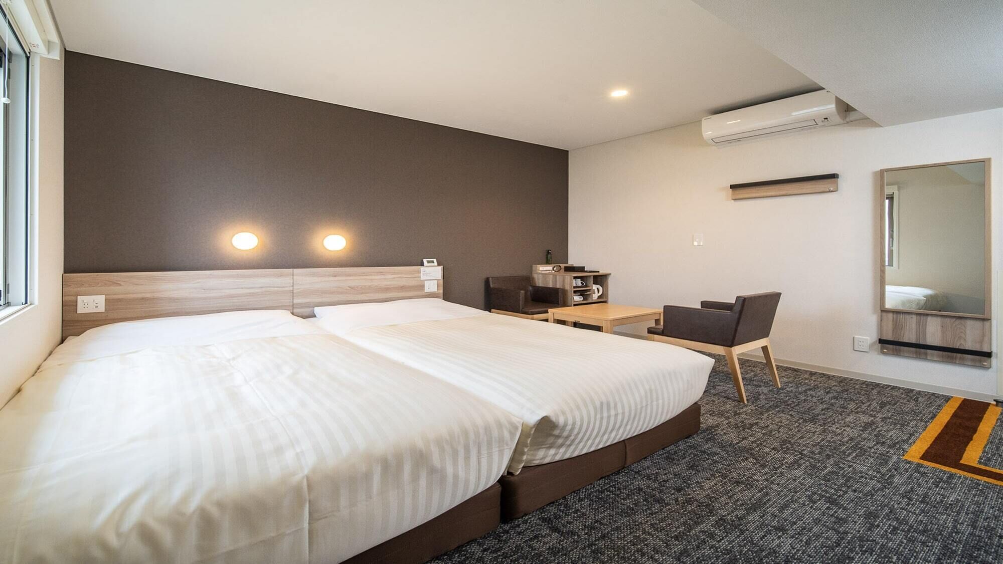 Quarto de hotel com uma cama grande, uma mesa, uma cadeira e um espelho.