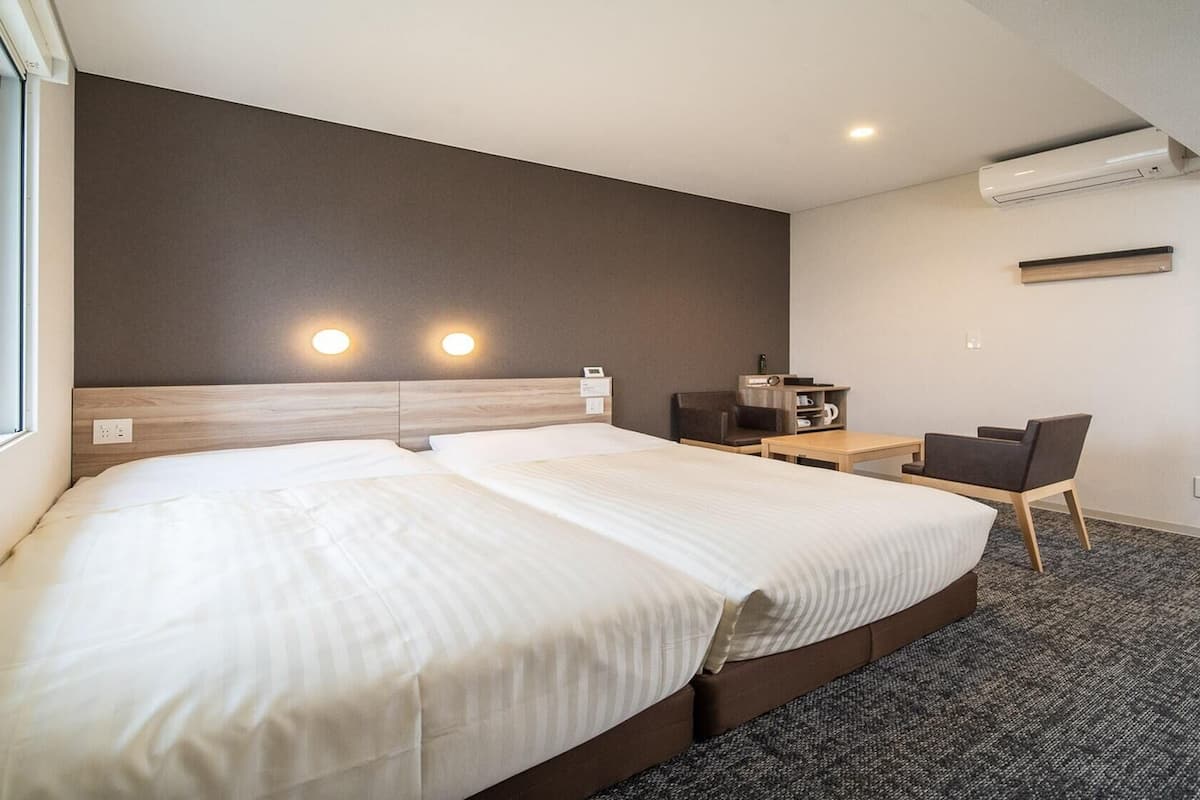 A hotel room with a large bed, a desk, a chair, and a mirror.