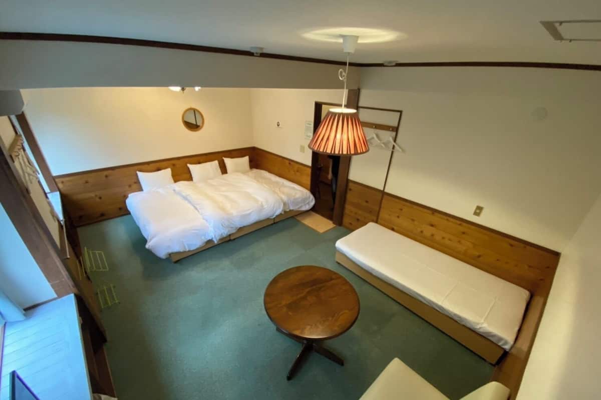 Ein Zimmer mit einem Bett, einem Sofa, einem runden Tisch und einer Lampe.