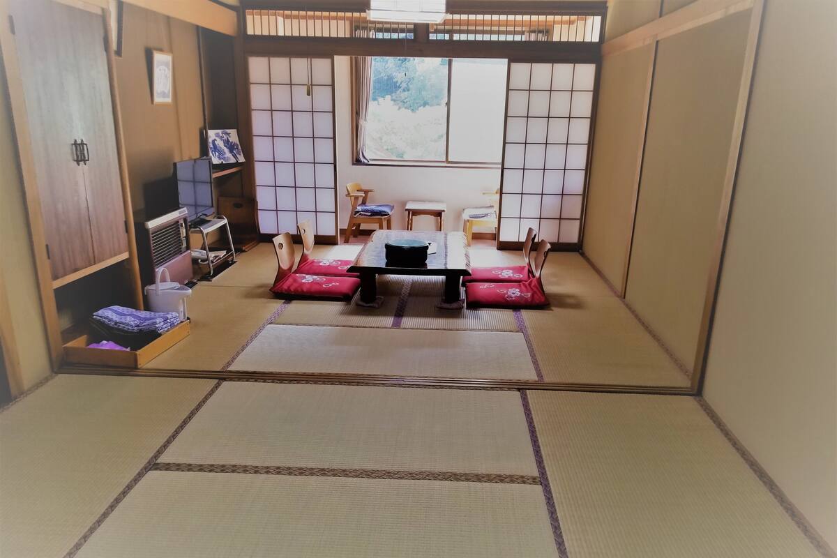 Een kamer met tatami matten, een lage tafel, stoelen en een futonbed.