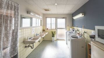 A hotel bathroom with multiple sinks, a mirror, a potted plant, and a laundry machine.