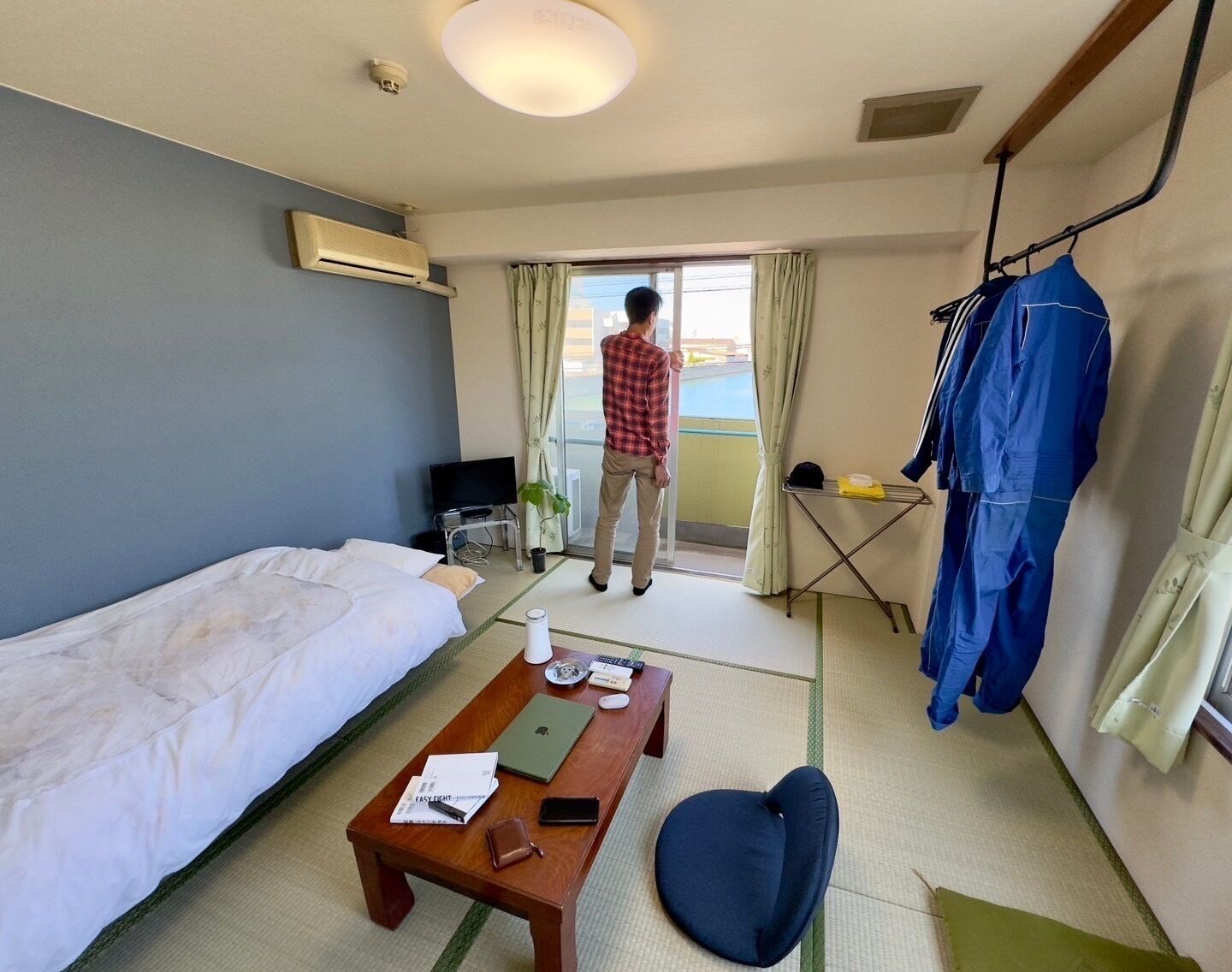 A hotel room with a bed, a desk, a chair, a table, a TV, and a window.