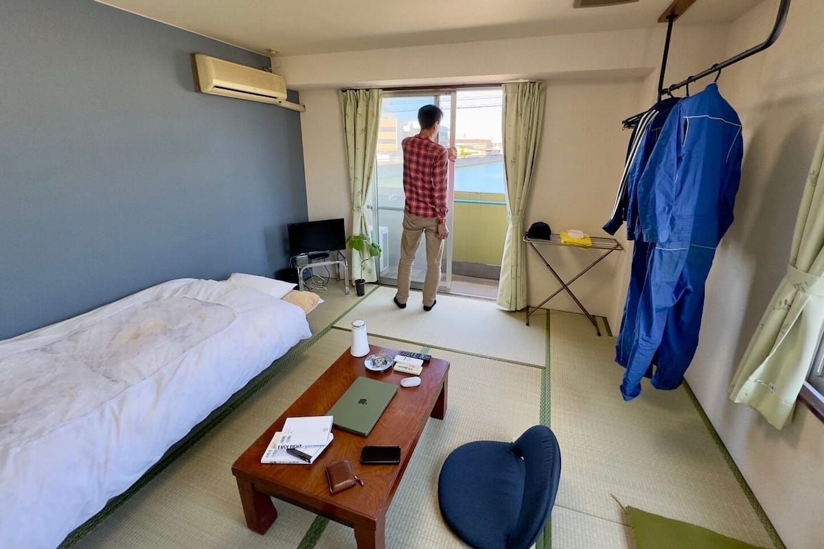 A hotel room with a bed, a desk, a chair, a table, a TV, and a window.