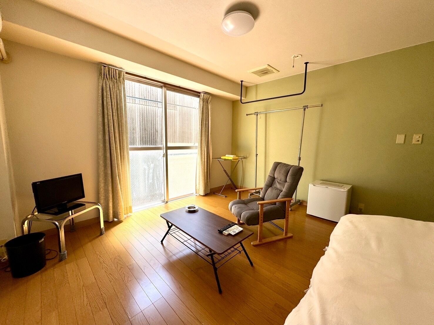 A hotel room with a television, a desk, a chair, a bed, and a window with curtains.