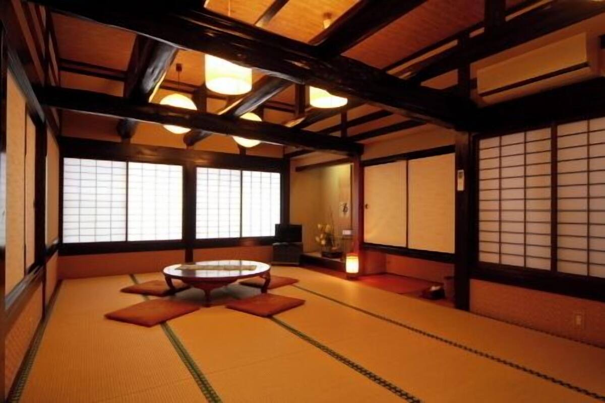 Une pièce avec un sol recouvert de tatamis, une petite table basse, des portes coulissantes et un décor intérieur japonais traditionnel.