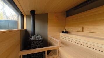 A sauna room with wooden walls, a black chimney, and a wooden bench.