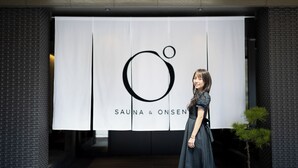 A person standing in front of a sign with 'SAUNA & ONSEN' written on it. - OND Hotel (Takeo)