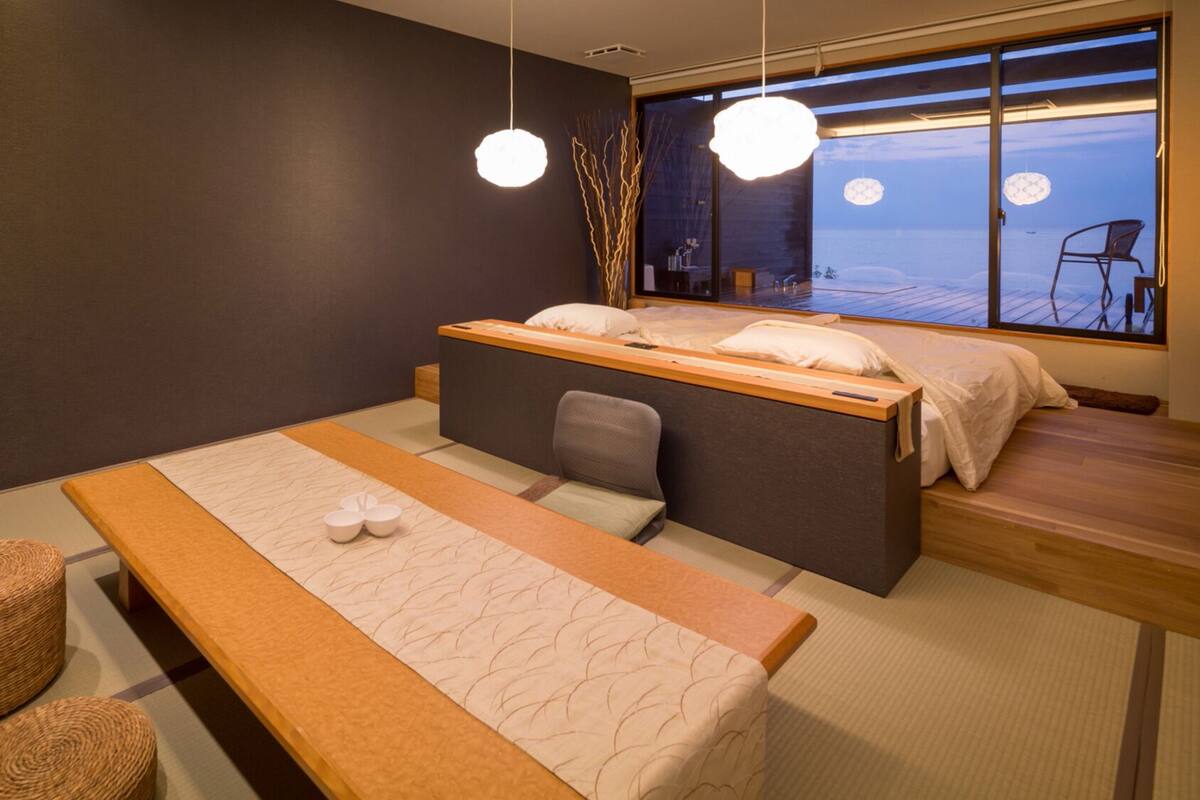 A modern room with a bed, a bench, and a view of the sea.