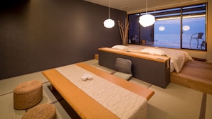 A modern room with a bed, a bench, and a view of the sea. - Tara Takezaki Onsen Kaijyoukan (Tara)