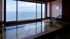 A large indoor swimming pool with a view of the sea, wooden flooring, and a small staircase leading to a door. - Tara Takezaki Onsen Kaijyoukan (Tara)