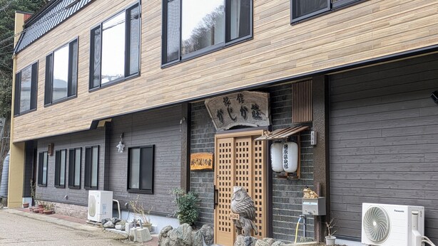 A two-story building with a wooden facade, large windows, and a traditional Japanese entrance gate. - Yubara Onsen Ryokan Kajikaso (Maniwa)