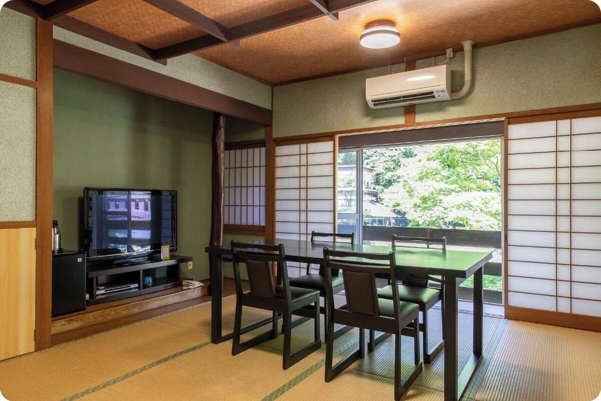 A traditional Japanese room with tatami flooring, a low table, and a television.