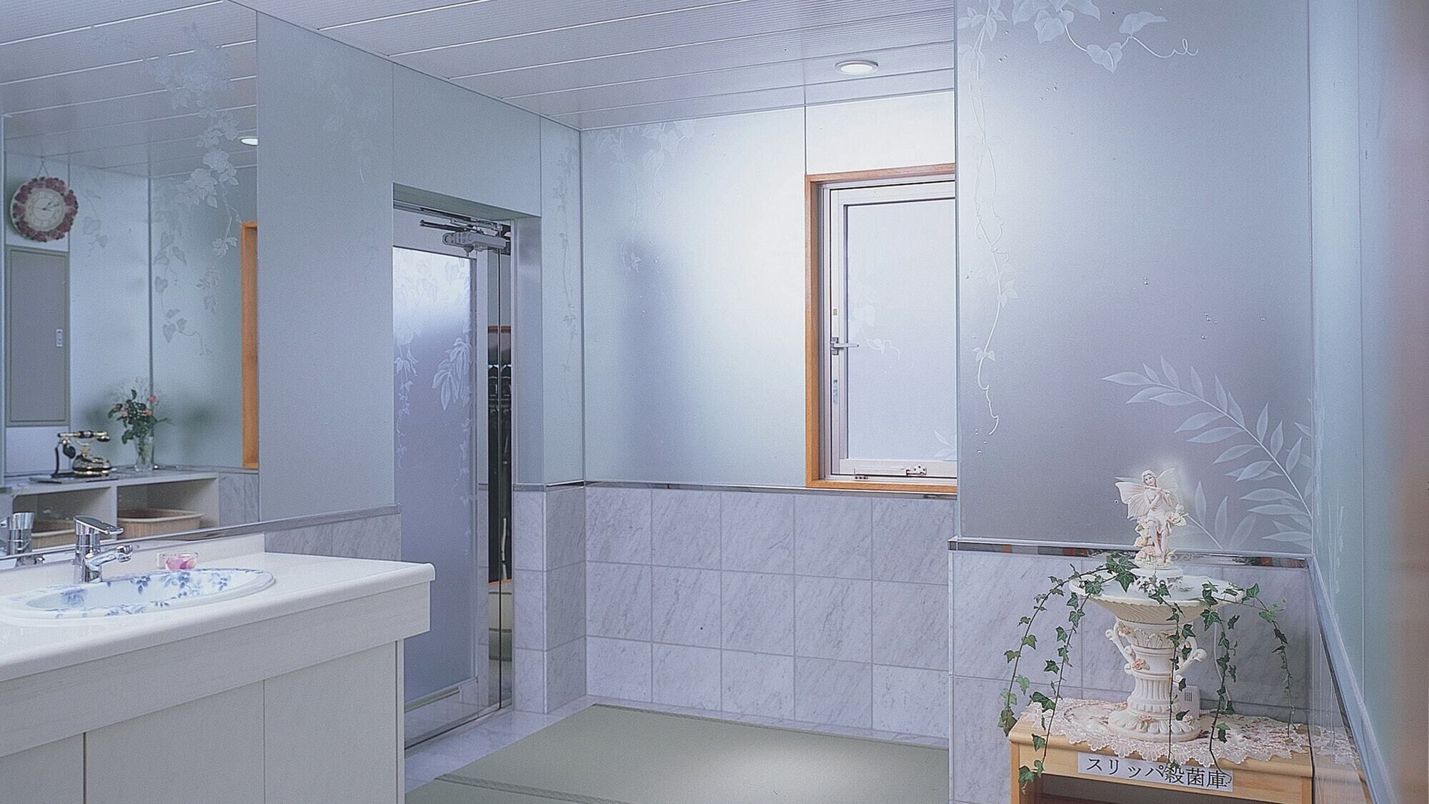 Un bagno con lavandino, specchio, doccia e una pianta decorativa.