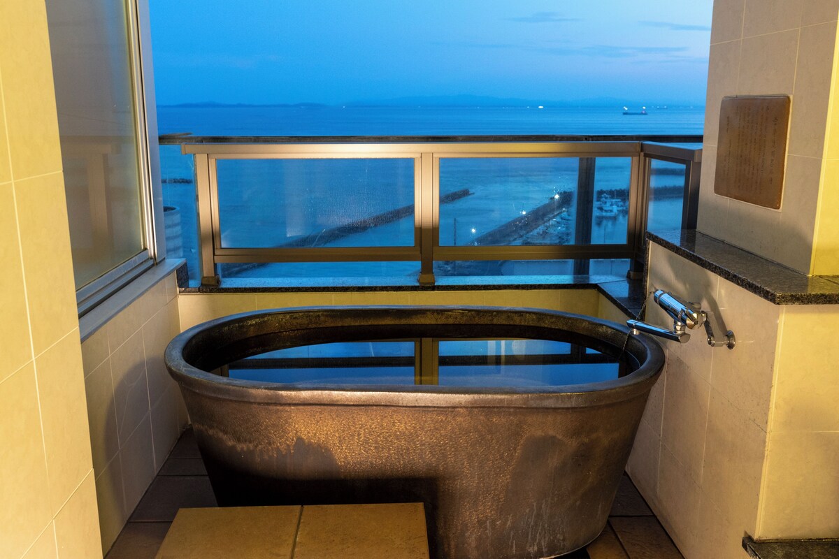 Una bañera en un rincón de una habitación con vista al mar.