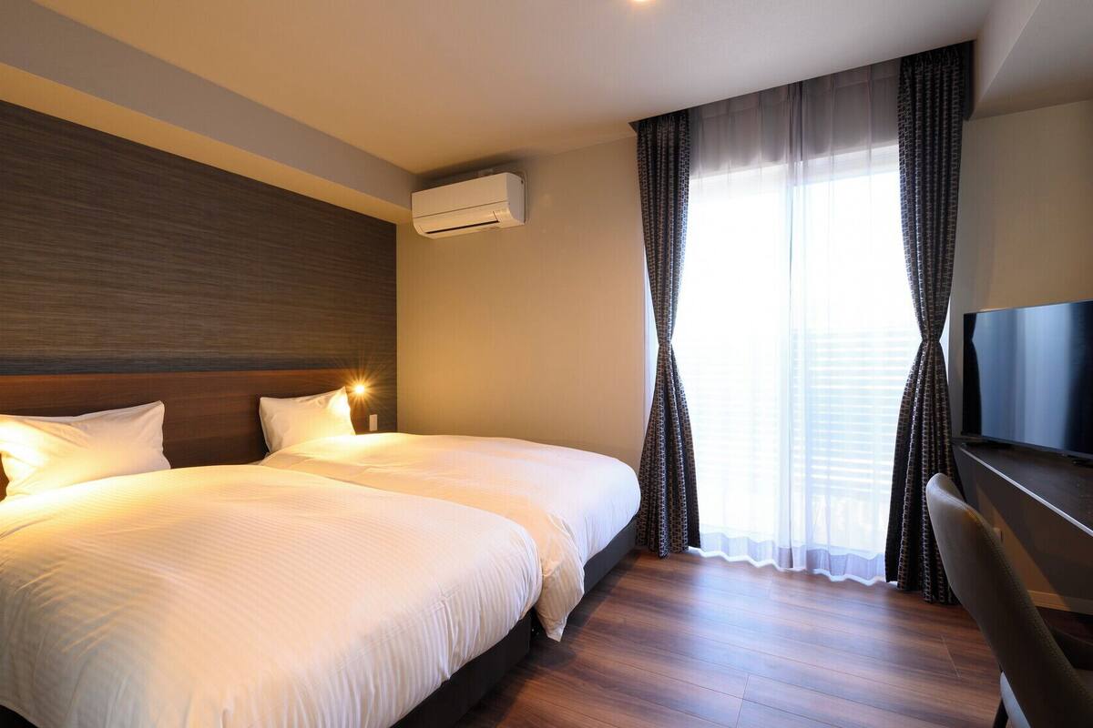Una habitación de hotel con dos camas, un televisor y un equipo de aire acondicionado.