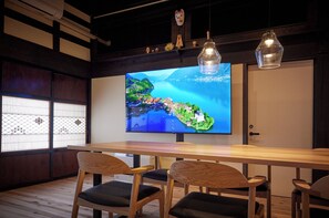 A modern interior with a large flat-screen TV displaying a scenic landscape, wooden furniture, and traditional decor elements.