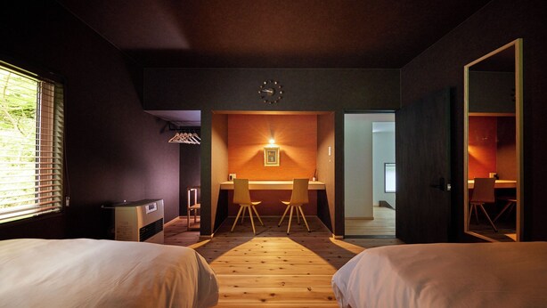 A hotel room with two beds, a desk, and a chair, with a view of the outdoors through a window. - Totonoi Kominka Villa Igashima (Aga)