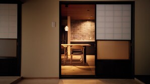 A room with a sliding door leading to a kitchen area, a wooden table, and a chair. - Totonoi Kominka Villa Igashima (Aga)