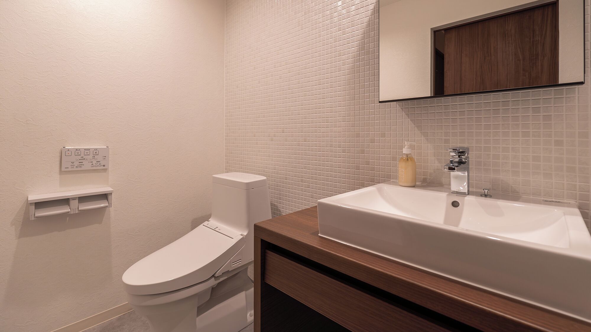 A bathroom with a toilet, a sink, and a mirror.