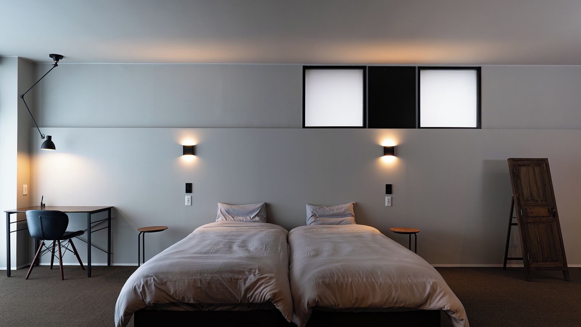 A room with two beds, a desk, a chair, and a ladder.