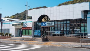 A modern building with a prominent entrance, a clear sky, and a hillside in the background. - Renovation Hotel Gobo (Gobo)