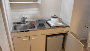A compact kitchen with a sink, a scale, a bowl, and a small dishwasher. - Renovation Hotel Gobo (Gobo)
