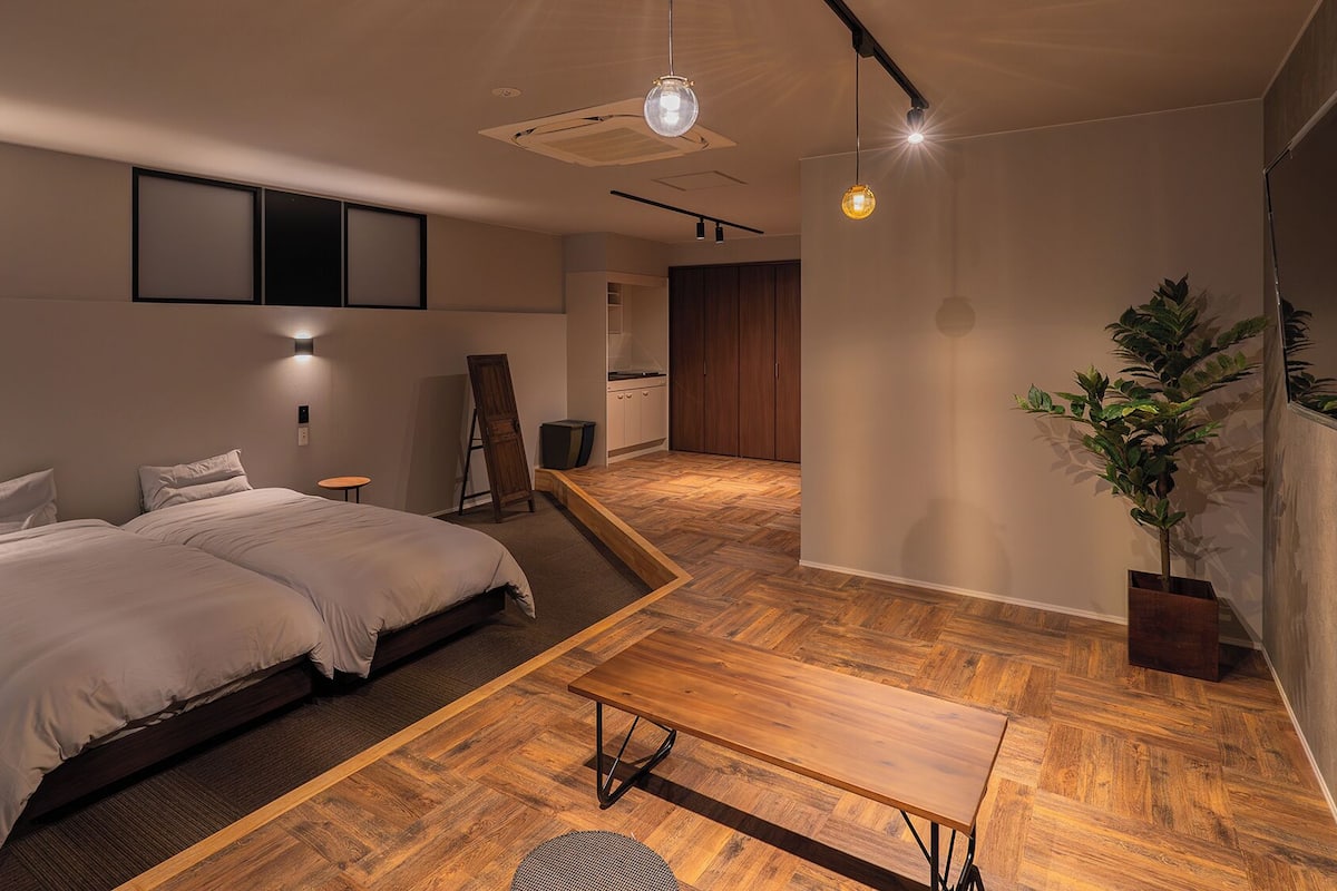 Ein modernes Schlafzimmer mit einem großen Bett, einem Holztisch und einem Topf mit einer Pflanze.