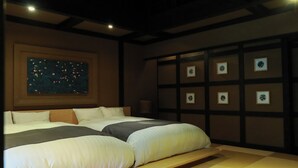 A hotel room with a large bed, a night sky painting, and a wall with framed pictures.