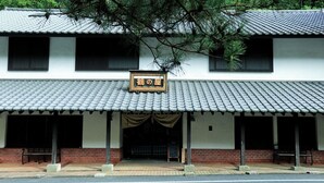 A traditional building with a tiled roof, a signboard, and a covered entrance with benches.