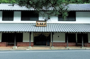 A traditional building with a tiled roof, a signboard, and a covered entrance with benches.