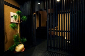 Een gang met een bloempot, een lijst met foto en een donker houten poort.