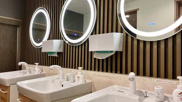 A bathroom with three sinks, each with a mirror and soap dispenser.
