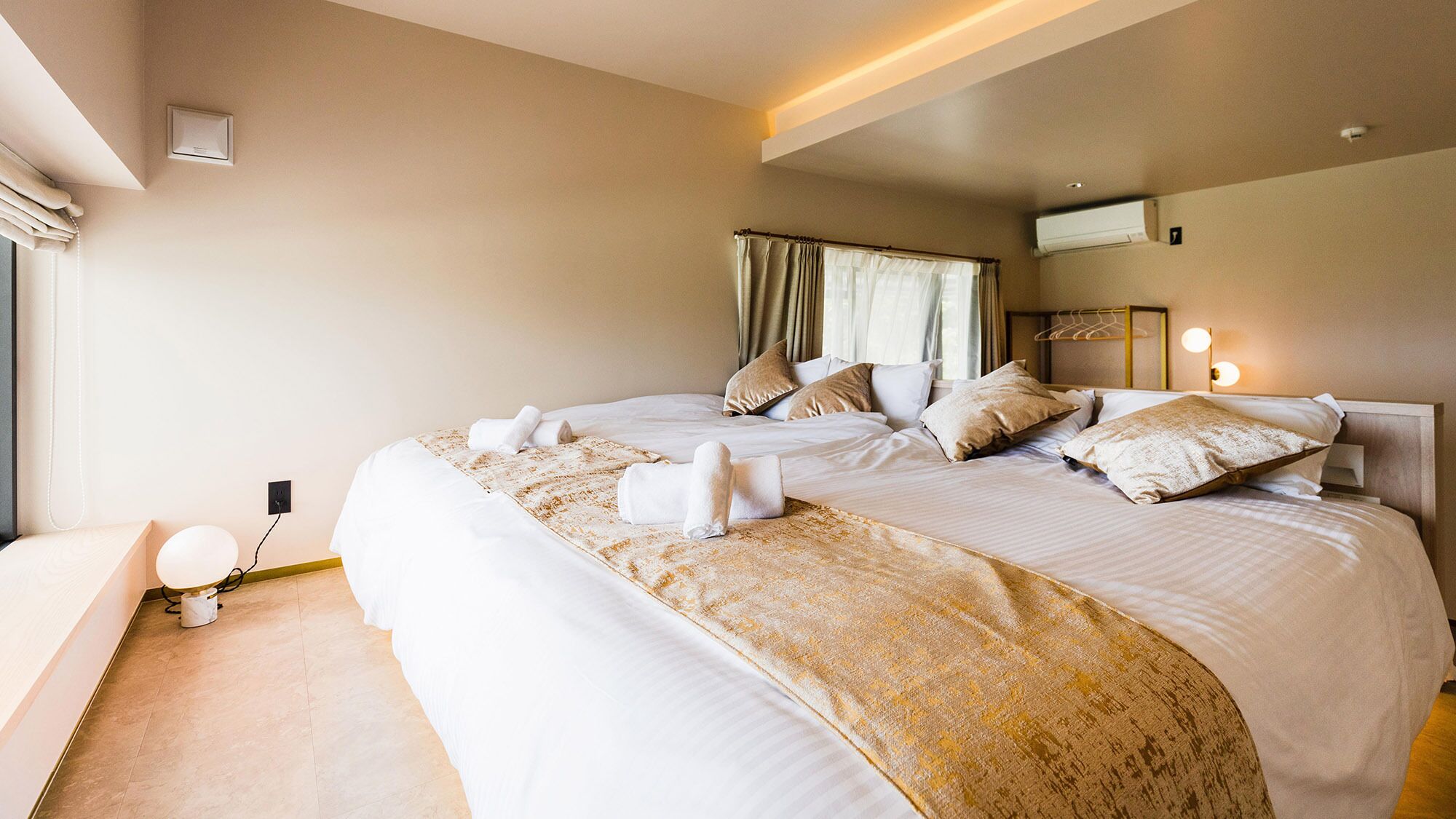 Une chambre d’hôtel avec un grand lit, une table de chevet, une lampe et une fenêtre avec des rideaux.