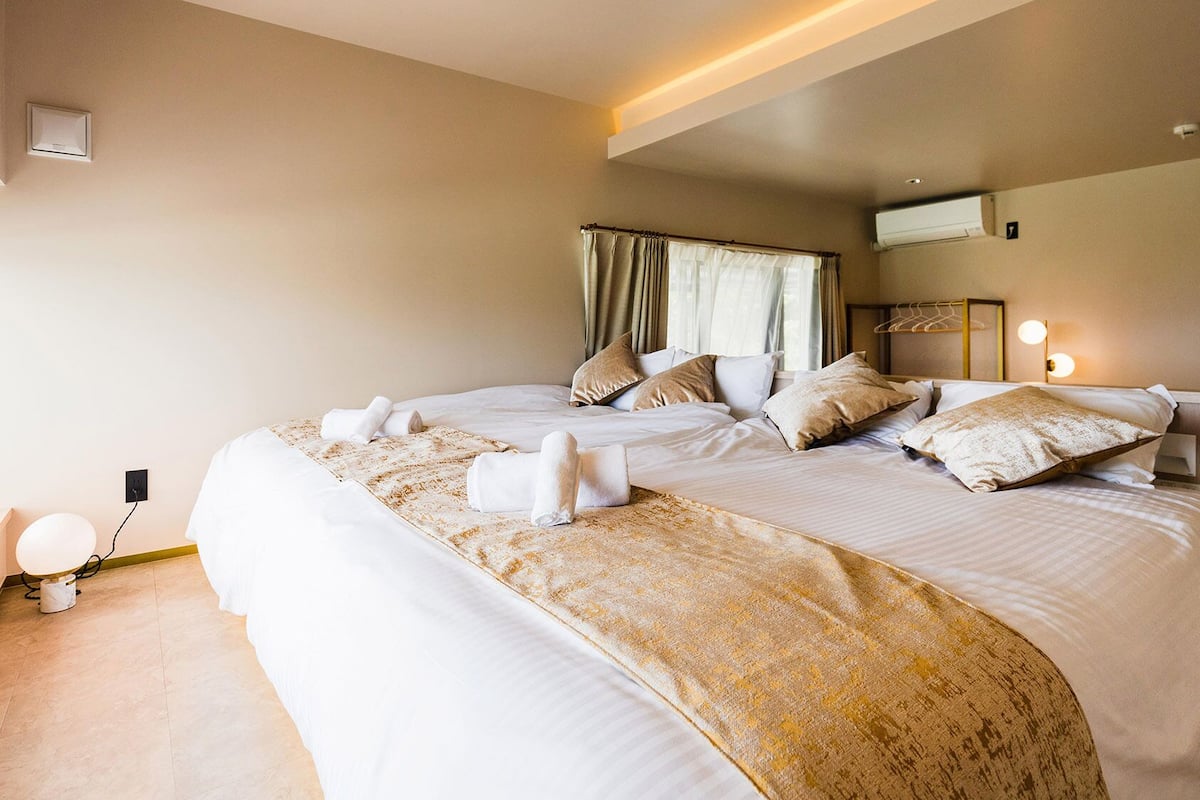 Une chambre d’hôtel avec un grand lit, des tables de chevet, une lampe de chevet et une fenêtre avec des rideaux.