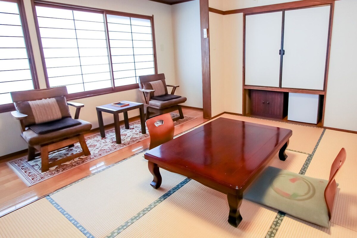 A traditional Japanese room with tatami flooring, a low wooden table, and a sliding door.